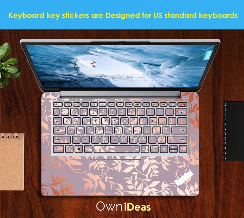Op de afbeelding: Laptop met toetsenbordstickers. De stickers hebben een bloemenpatroon in roze en oranje tinten. Het scherm toont een landschap. De tekst luidt: "Keyboard key stickers are Designed for US standard keyboards".