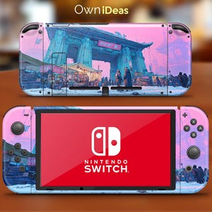 May include: A Nintendo Switch console with a custom skin featuring a pink and blue cityscape design. The skin wraps around the console and Joy-Cons, with the Nintendo Switch logo visible on the screen. The top of the console has the text "OwniDeas".