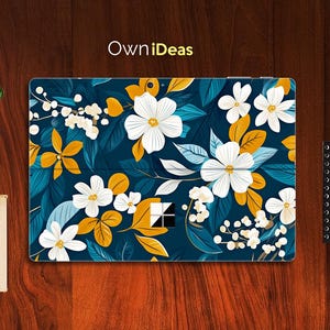 Puede incluir: Una piel para portátil azul con un diseño floral que presenta flores blancas, hojas amarillas y follaje verde. El diseño se repite en toda la superficie de la piel. El texto "OwnIdeas" está impreso en amarillo en la parte superior de la piel.