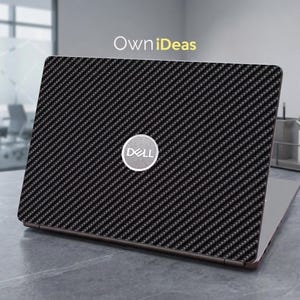 May include: A Dell laptop with a black carbon fiber textured skin. The laptop has a silver Dell logo on the back and the text "OwniDeas" in the upper left corner. The laptop is on a gray surface.