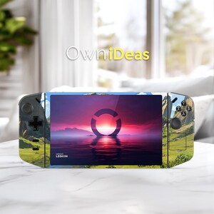 May include: A handheld gaming console with a landscape design. The screen displays a sunset over water with a circular design. The console has black buttons and a black joystick. The text "Lenovo Legion" is visible.
