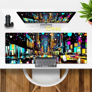 Puede incluir: Una escena colorida de una calle de la ciudad con luces brillantes y coches conduciendo por la calle. La escena está representada en una alfombrilla de ratón negra con un teclado delante.