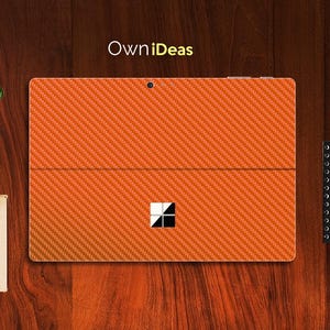 Op de afbeelding: Oranje laptop-huid van carbon fiber met het Microsoft-logo. OwnIdeas is op de huid gedrukt.