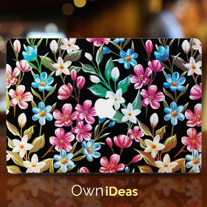 Könnte beinhalten: Eine schwarze Laptop-Haut mit einem Blumenmuster mit rosa, blauen, weißen und grünen Blumen auf schwarzem Hintergrund. Die Haut ist für einen Laptop konzipiert.