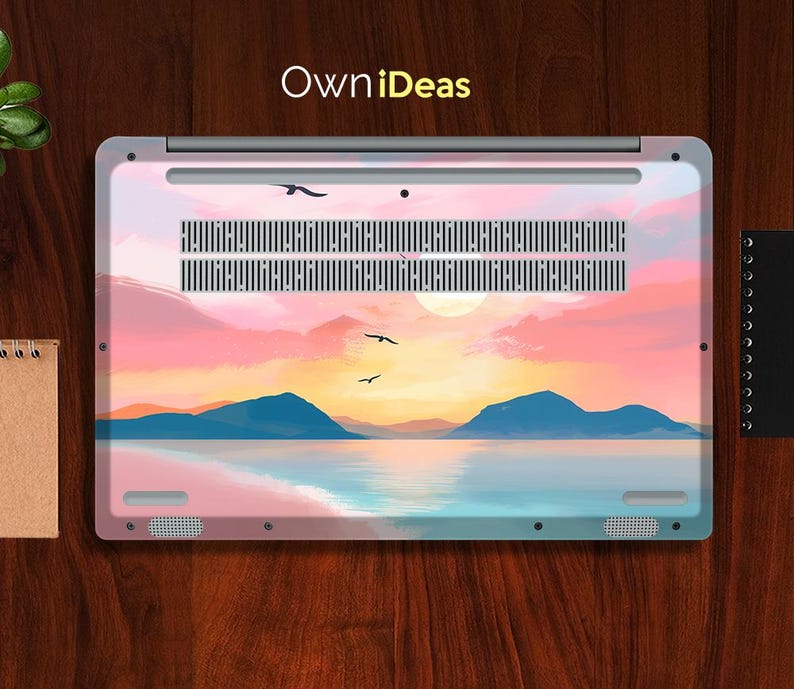 Op de afbeelding: Laptop skin met een zonsondergang, met een levendige lucht in roze, oranje en geel. Het ontwerp toont silhouetten van bergen, water en vogels in vlucht. De tekst "OwniDeas" is rechtsboven zichtbaar.