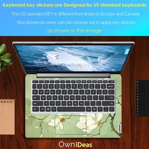 May include: A laptop computer with a green and white floral keyboard sticker. The sticker features a magnolia flower design. The text "Own iDeas" is printed on the bottom of the image. The text "Lenovo" is printed on the bottom right corner of the laptop.