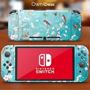 May include: A turquoise Nintendo Switch console skin with a floral design featuring cherry blossoms and birds. The skin has a light blue background with white flowers and brown birds. The Nintendo Switch logo is visible on the screen.
