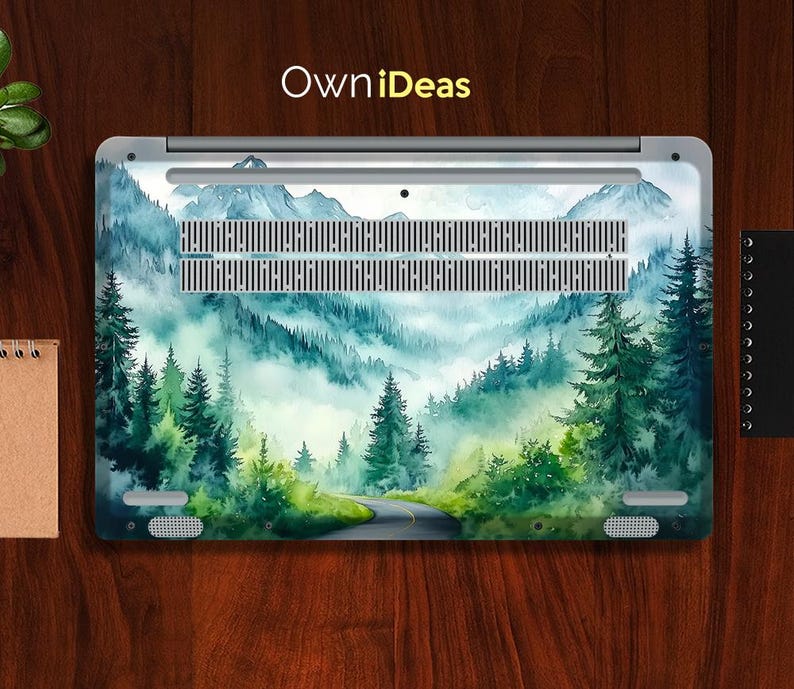 May include: A laptop skin with a watercolor design of a misty forest scene. The design features a winding road through the trees and a light blue sky.