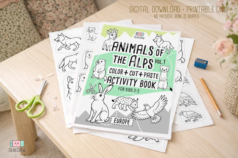 Printable “Animals of the Alps Vol. 1” color, cut-and-paste activity book cover shown with sample black-and-white alpine animal pages spread on a wooden table with scissors and pencils, labeled as a digital download.