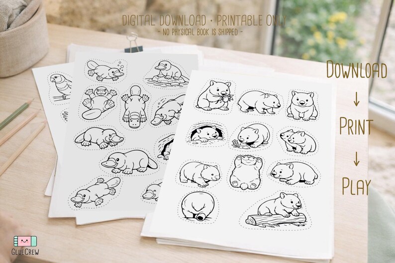 Sample black-and-white cut-and-paste animal pages with dashed cutting lines, shown stacked on a wooden desk and labeled as a digital download printable activity book.