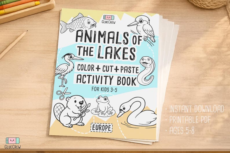 Cover mockup of the printable PDF “Animals of the Lakes” color, cut-and-paste activity book, shown as a stacked booklet on a wooden table with illustrated lake animals on the front cover.