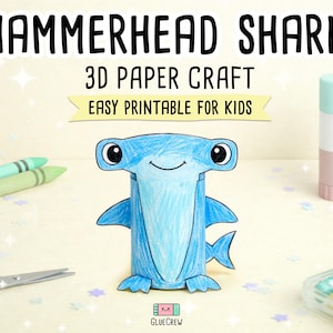 以下が含まれることがあります： 「HAMMERHEAD SHARK 3D PAPER CRAFT EASY PRINTABLE FOR KIDS」の文字が入った、青い3Dペーパークラフトのシュモクザメ。 クレヨン、ハサミ、のりなどの画材に囲まれています。