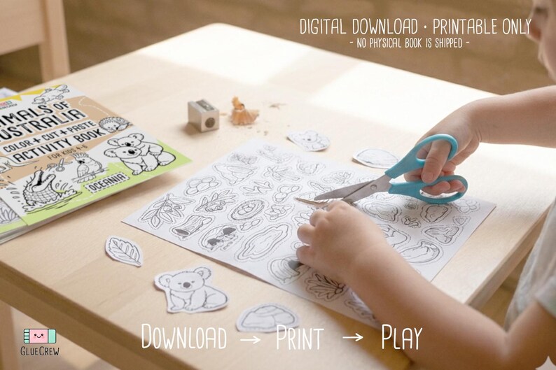 Child cutting out black-and-white animal shapes with scissors from a printable activity page, with the “Animals of Australia” book visible on a wooden desk, labeled as a digital download printable.