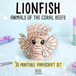 Puede incluir: Un pez le&oacute;n de papel en 3D con patrones de rayas beige y marrones, ojos negros grandes y una boca fruncida. El texto dice LIONFISH ANIMALS OF THE CORAL REEFS y 3D PRINTABLE PAPERCRAFT SET. Se observan materiales de manualidades alrededor.