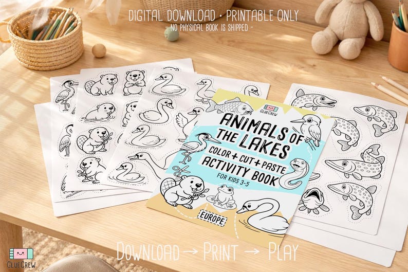 Digital download printable “Animals of the Lakes” color, cut-and-paste activity book for kids 3–5, shown with cover and sample black-and-white animal pages spread on a wooden desk with crayons.