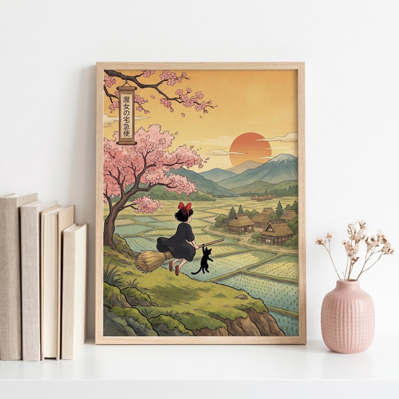 May include: A framed print featuring a young witch on a broom with a black cat, flying over a rural landscape with rice paddies and traditional Japanese houses. The artwork has a warm color palette with a sunset and cherry blossom tree.