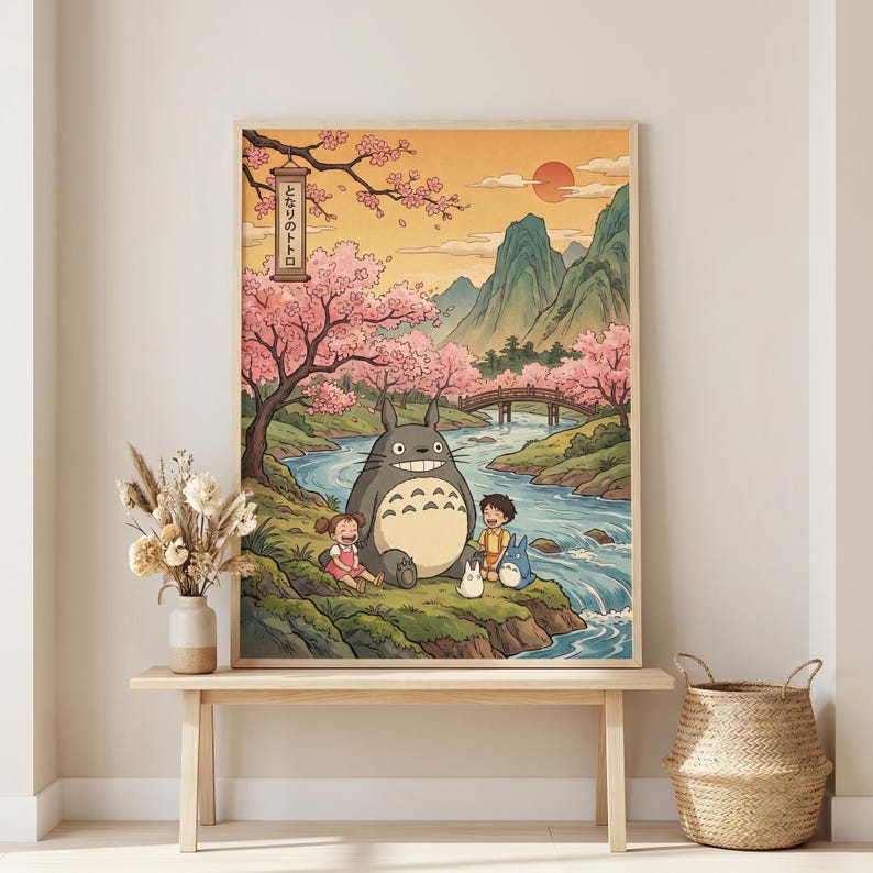 May include: A framed art print featuring a scene from the animated film, My Neighbor Totoro. The artwork depicts Totoro with two children and two smaller creatures near a river, with a bridge, mountains, and cherry blossoms in the background. The Japanese text is visible.