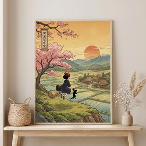 May include: A framed art print featuring a young witch on a broom with a black cat, flying over a rural landscape with rice paddies, mountains, and a setting sun. The print has Japanese text and cherry blossoms.
