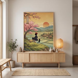 May include: A framed art print depicting a witch on a broom with a black cat, set against a rural landscape with a sunset and cherry blossoms. The artwork has a Japanese aesthetic and features text in the upper left corner.