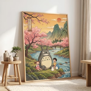 May include: A framed art print featuring a scene from the animated film, My Neighbor Totoro. The artwork depicts Totoro with two children near a river, under cherry blossom trees. The background includes mountains, a bridge, and a setting sun. The Japanese text is visible.