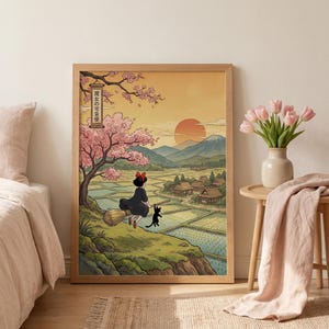 May include: A framed art print featuring a young witch flying on a broom with a black cat, set against a Japanese landscape. The artwork includes cherry blossoms, rice fields, and a sunset. The text in the image reads "魔女の宅急便".