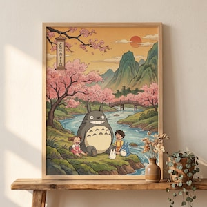 May include: A framed print featuring a scene from the animated film, My Neighbor Totoro. The artwork depicts Totoro, two children, and two smaller Totoros near a river, with a bridge, mountains, and cherry blossom trees in the background. The text "となりのトトロ" is visible.