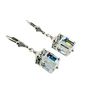 May include: A pair of silver dangle earrings with clear crystal cube charms. Each charm is accented with a silver setting and smaller clear crystals.