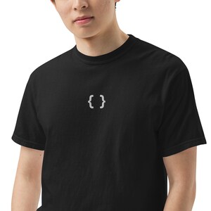 May include: Black t-shirt featuring a small, white, embroidered curly brace symbol. The shirt has a crew neck and short sleeves. The fabric looks soft and comfortable. The design is simple and minimalist.