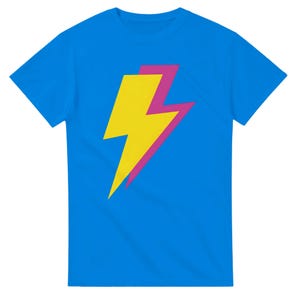 May include: A bright blue short-sleeved t-shirt featuring a large, centred graphic of a yellow lightning bolt layered over a slightly offset magenta lightning bolt. The design is simple, bold, and occupies the centre of the chest area.