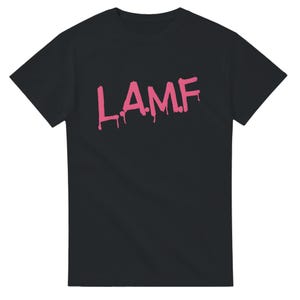 Puede incluir: Una camiseta negra de manga corta con el texto L.A.M.F. impreso en rosa en el pecho, con un estilo de pintura que gotea. La prenda cuenta con un cuello redondo estándar y un dobladillo recto, ofreciendo una silueta sencilla y limpia al vestir.