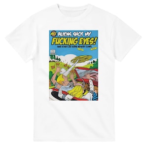 May include: White t-shirt with a comic book-style graphic. The graphic reads "ALIENS SHOT MY FUCKING EYES!" with an illustration of a car, aliens, and people. The shirt has a crew neck and short sleeves.