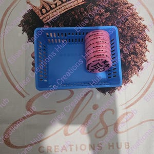 May include: A rectangular blue plastic storage basket containing a stack of circular pink tokens. Each token features a black printed pattern of four-pointed stars and floral motifs, with the text Louis Vuitton visible on the top token surface.