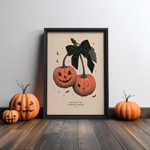 May include: A framed art print featuring two orange jack-o'-lanterns tied together with a large black bow. The illustration includes small stars, crescent moons, and bats. The text "MEET ME AT THE PUMPKIN PATCH" is printed at the bottom centre.