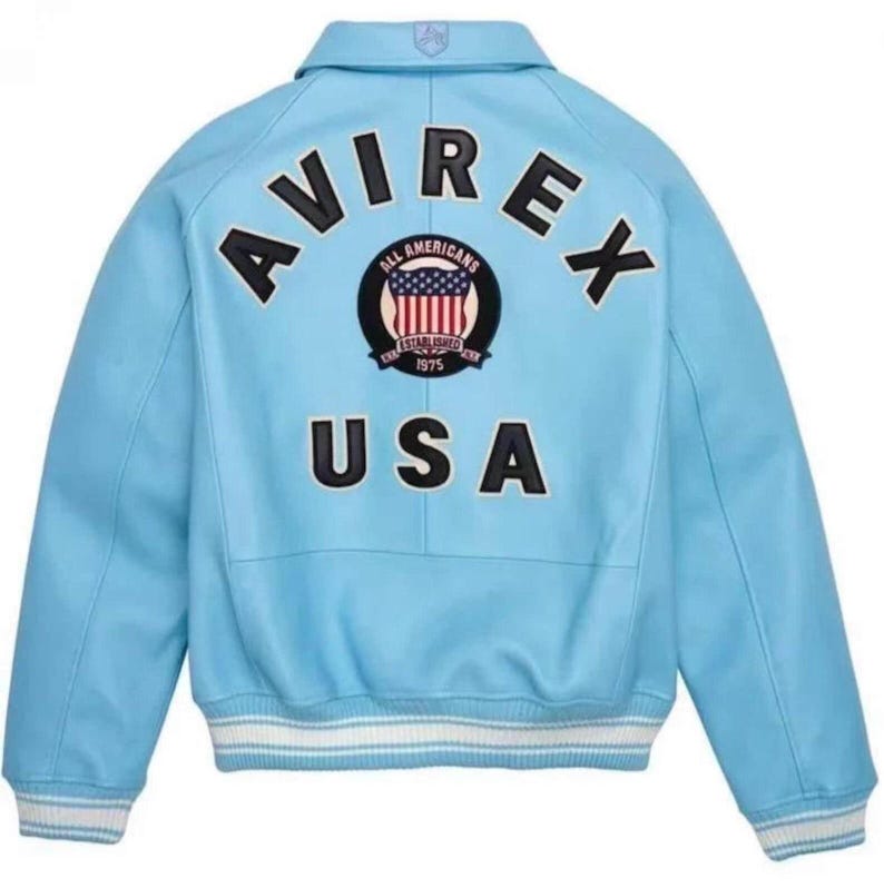 May include: Light blue leather jacket with the word "AVIREX" arched across the back in black lettering. Below the word "AVIREX" is a circular emblem with the words "ALL AMERICANS" and "ESTABLISHED 1975". The word "USA" is printed below the emblem.