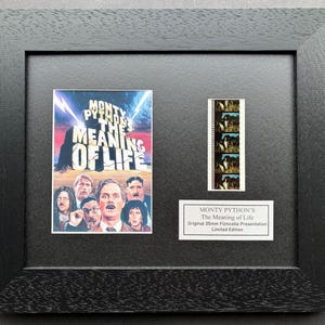 May include: Framed print of the film poster for "Monty Python's The Meaning of Life." The poster is colourful, with the film's title and cast images. Includes a film strip and a plaque with text, all within a black frame.