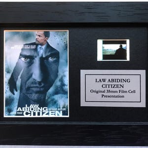 May include: Framed "Law Abiding Citizen" film cell presentation. The black frame contains a movie poster image, a small film cell, and a plaque. The poster features Jamie Foxx and Gerard Butler.