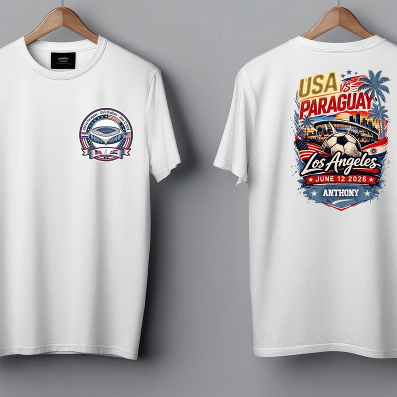 Front and back view of a white t-shirt on hangers featuring a small chest badge on the front and a large colorful soccer graphic on the back reading “USA vs Paraguay, Los Angeles, June 12 2026, Anthony.” The design includes a stadium, soccer ball, palm trees, skyline, and American flag elements. Clean product mockup showcasing a personalized sports fan tee for match day and soccer events.