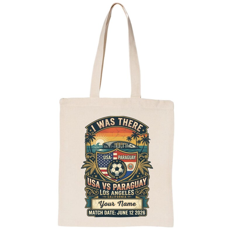 Natural canvas tote bag featuring a personalized vintage-style “I Was There” USA vs Paraguay soccer match design. Graphic includes a sunset stadium scene, palm trees, soccer ball, USA and Paraguay flags, “Los Angeles California,” customizable name text, and “Match Date: June 12 2026.” Reusable eco-friendly tote bag mockup on a plain light background, perfect personalized soccer fan gift, match day souvenir, and everyday carryall bag.