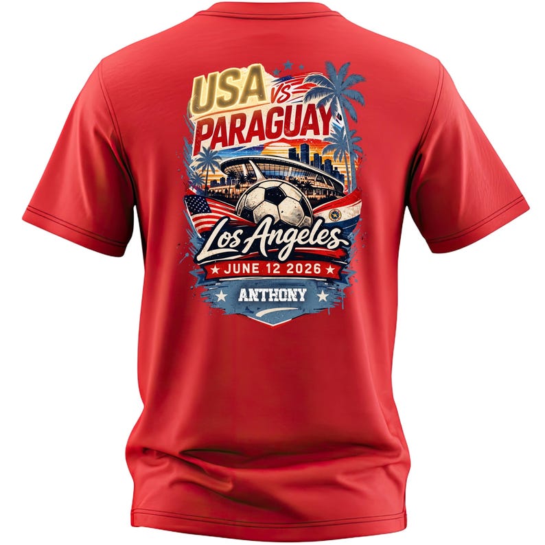 Back view of a red t-shirt featuring a bold soccer match design reading “USA vs Paraguay, Los Angeles, June 12 2026, Anthony.” The graphic includes a stadium, soccer ball, palm trees, city skyline, and American flag elements in vibrant red, white, and blue. Clean product mockup highlighting a personalized sports fan tee perfect for soccer events and match day wear.
