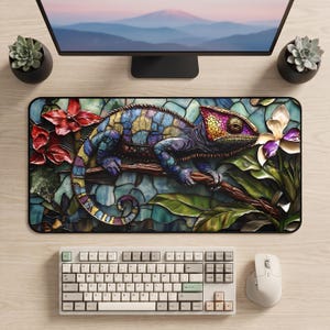 Pode incluir: Um tapete de secretária retangular com um camaleão multicolorido com um padrão de mosaico pousado num ramo. O design inclui flores vermelhas e orquídeas brancas sobre um fundo de vitral em tons de azul e verde.