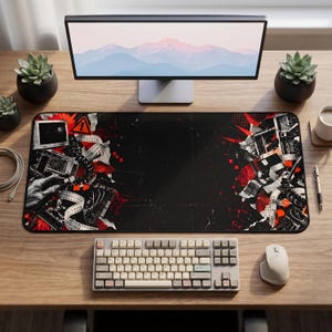 May include: A rectangular desk mat featuring a black background with red and white abstract graphic elements, including a film strip, a warning sign, and technical components. The design is concentrated on the left and right edges of the mat.