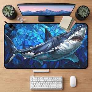 Peut inclure: Tapis de bureau rectangulaire avec une illustration stylisée d'un grand requin blanc dans des tons de bleu, blanc et gris. Le requin a un effet de vitrail. Le tapis est sur un bureau en bois avec un clavier, une souris et un écran.