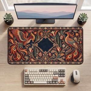 Könnte beinhalten: Eine rechteckige Schreibtischunterlage mit dunkelblauem Hintergrund, verziert mit zwei symmetrischen Phönixen, Granatäpfeln und floralen Mustern in Rot-, Orange- und Goldtönen. Die Unterlage liegt auf einem Holztisch mit Monitor, Tastatur, Maus und zwei kleinen Sukkulenten in Töpfen.
