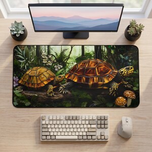 May include: A rectangular desk mat featuring a detailed illustration of two turtles with brown patterned shells and yellow-spotted skin, positioned in a lush green forest setting with white flowers and brown mushrooms on the forest floor.