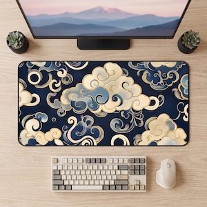 May include: A rectangular desk mat featuring a dark navy blue background with a repeating pattern of stylized cream and light blue swirling clouds. The design includes intricate gold-toned outlines around each cloud formation, creating a layered effect across the entire surface of the mat.