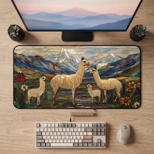 May include: A rectangular desk mat featuring a stained glass style illustration of four llamas standing in a mountain landscape with flowers. The design includes blue, gold, and green tones, with a black border, positioned on a wooden desk surface.