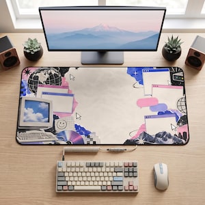 May include: A rectangular desk mat featuring a collage of retro computer graphics, including a vintage monitor displaying a blue sky, floating browser windows, cursor arrows, a globe, a smiley face, and abstract blue and pink watercolour shapes.