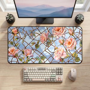 May include: A rectangular mouse pad featuring a floral design of pink roses and green leaves against a blue sky background with a wire fence overlay. A keyboard and mouse are visible.