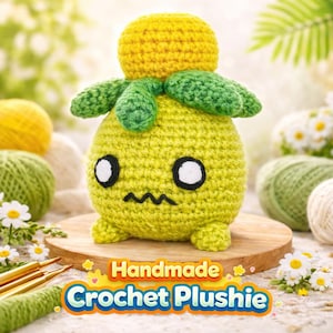 May include: A handmade crochet plushie in the shape of a yellow and green creature with a round head, green leaves, and a frowning face. The plushie has white eyes and is sitting on a wooden surface. The text "Handmade Crochet Plushie" is displayed below.