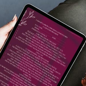 May include: A digital tablet displaying a Lash Lift & Brow Lamination consent form. The form is in a dark burgundy color with white text and floral accents. A white stylus rests beside the tablet. The image is taken from a top-down perspective.